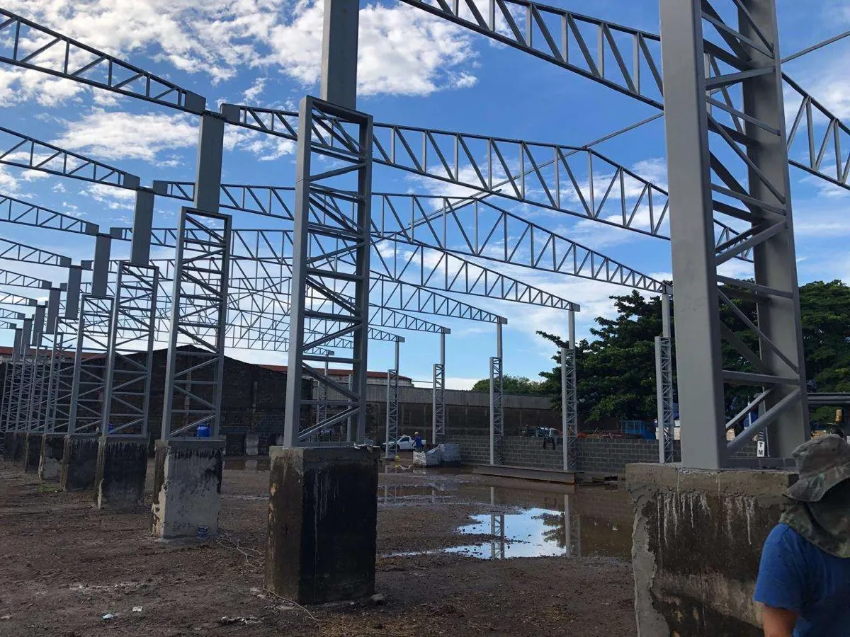 Montagem de estrutura metálica com treliças contra o céu